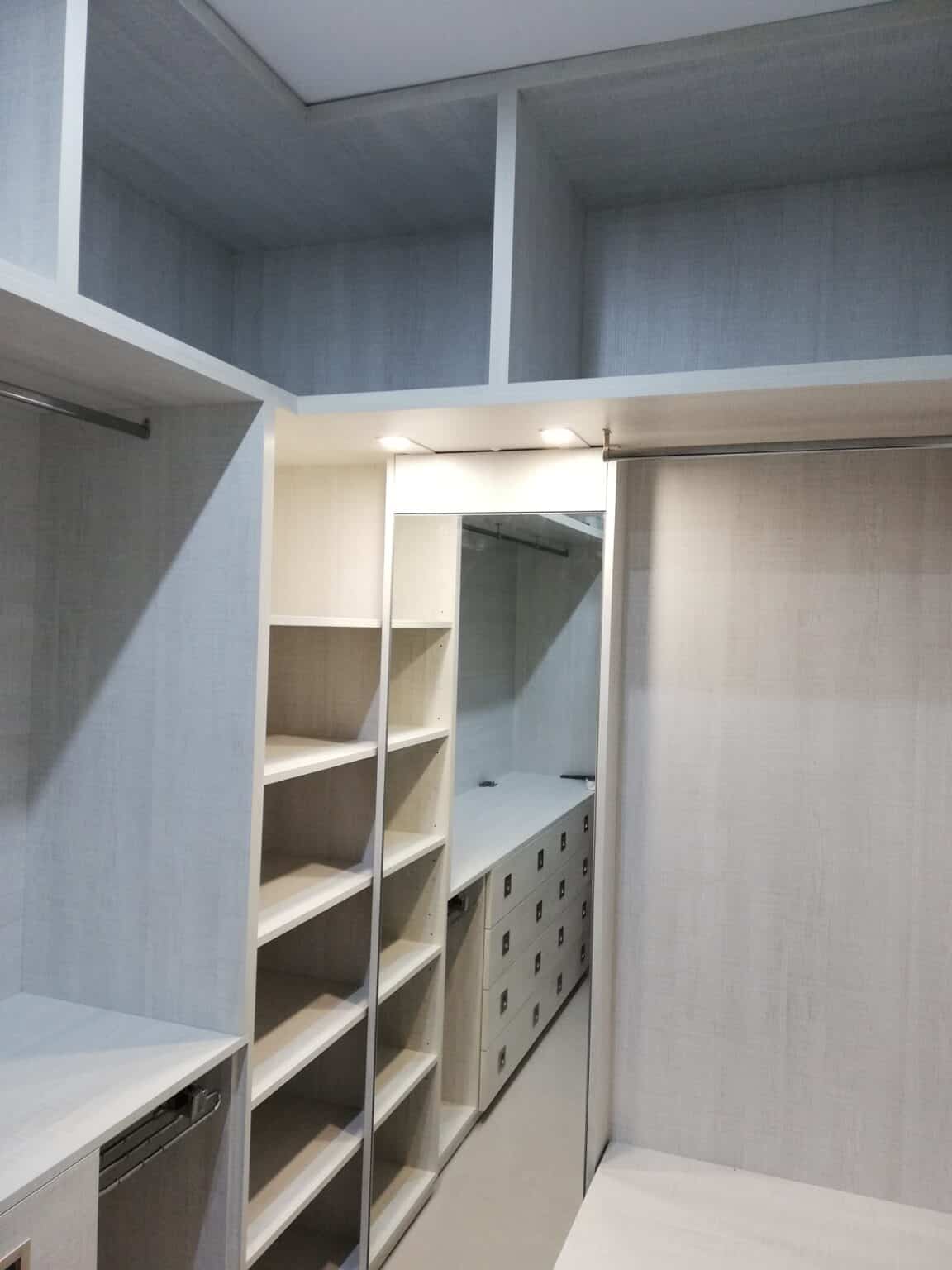 Interior de vestidor a medida con baldas, cajones e iluminación